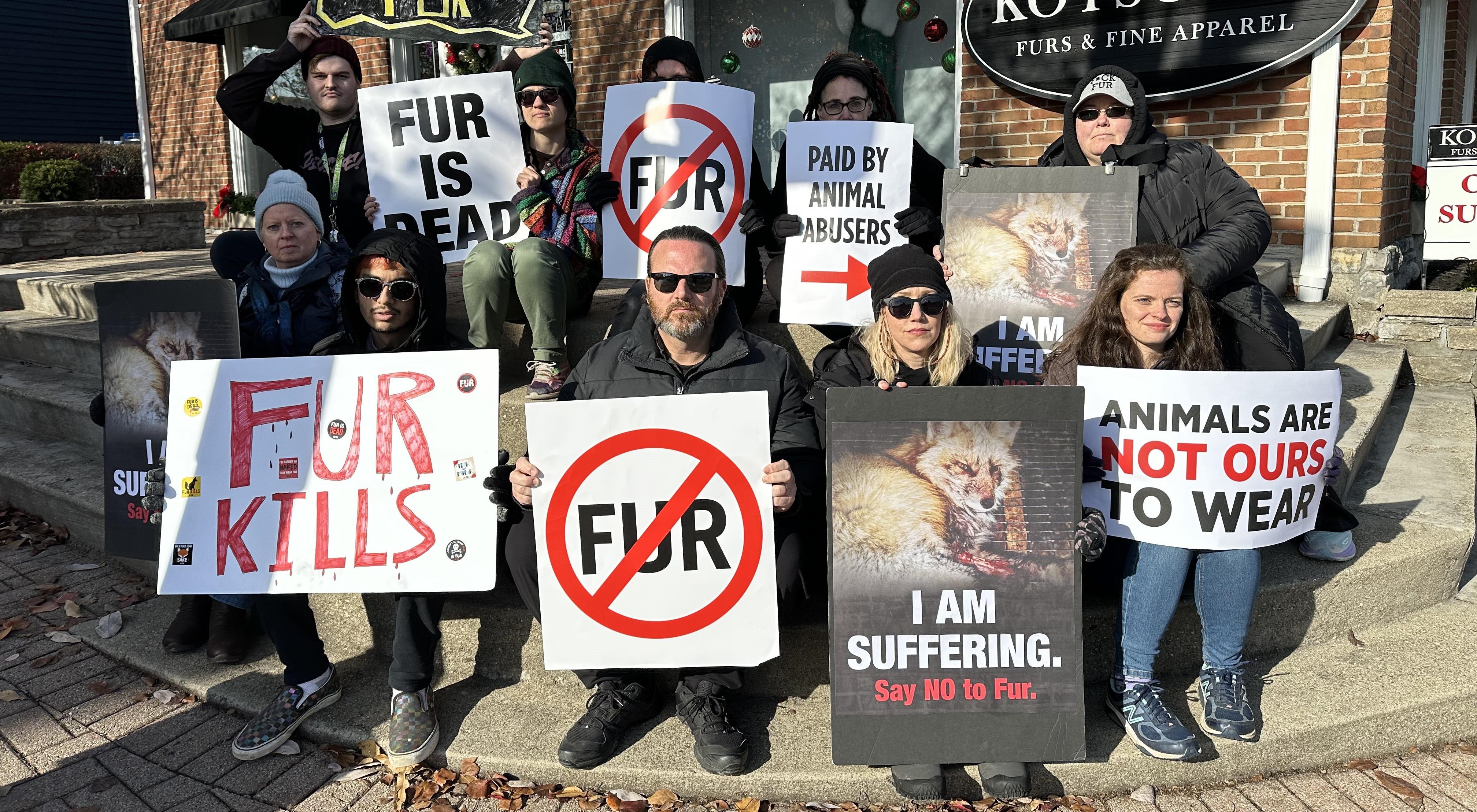 Fur protesters with signs standing outside a fur shop